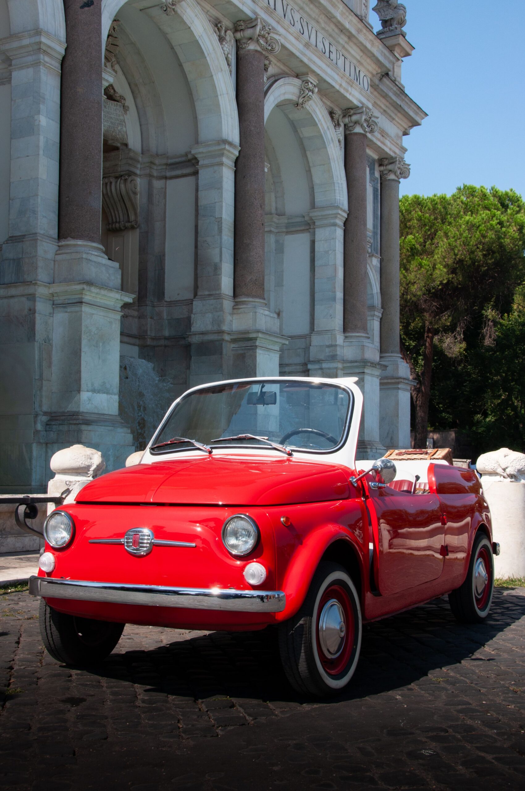The Art of Drawing Readers In: Your attractive post title goes here Classic red Fiat 500 cabriolet parked by an ancient Italian archway.
